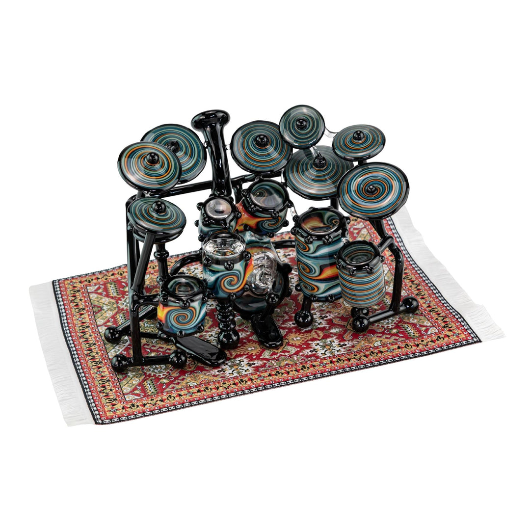 "AJ Roberts Wig Wag Drum Set heady functional glass piece on a colorful rug with a white background," - Up N Smoke.