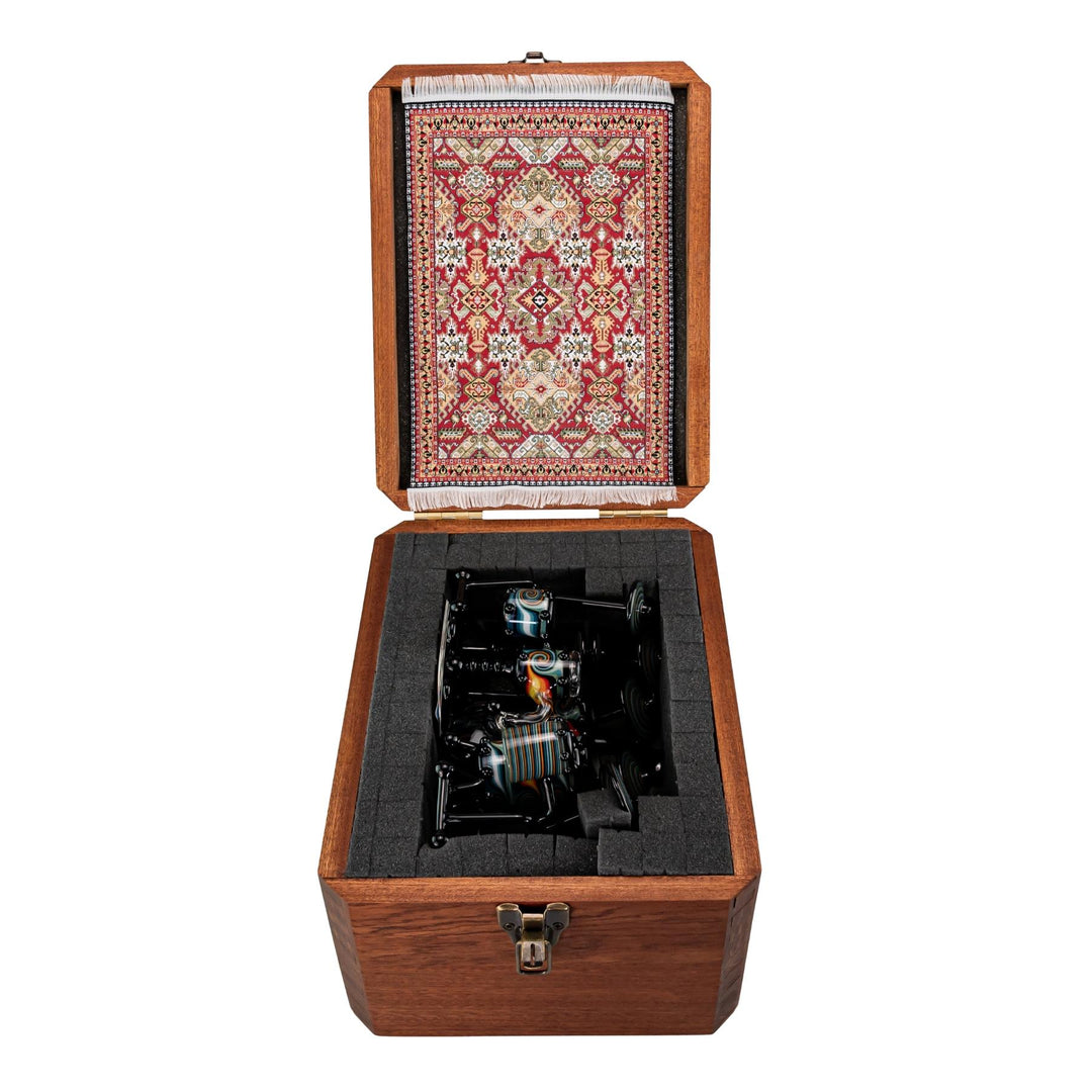 "Open wooden storage box that contains a decorative rug placemat and an AJ Roberts Wig Wag Drum Set on a white background," - Up N Smoke.