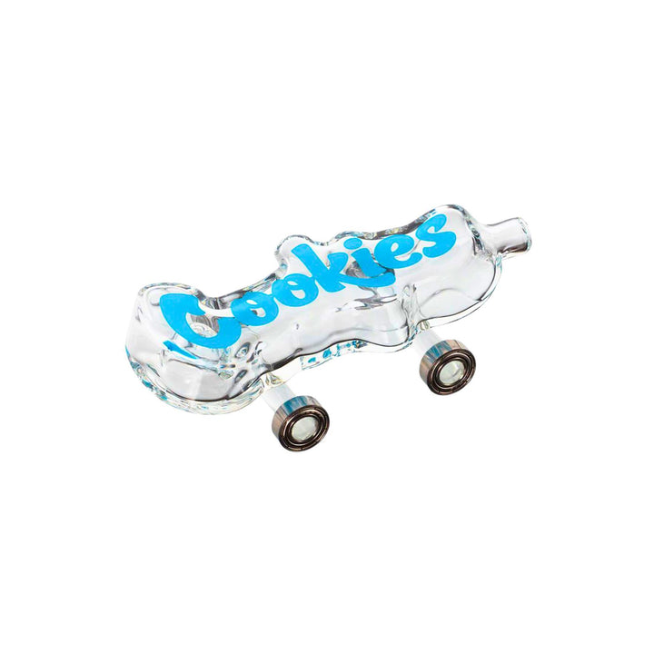 "Side photograph of a clear Cookies Toke Deck hand pipe. This piece looks like a skateboard and features functional wheels attached to the bottom. The bowl for flower is on the underneath, with the mouthpiece at the front." - Up N Smoke.