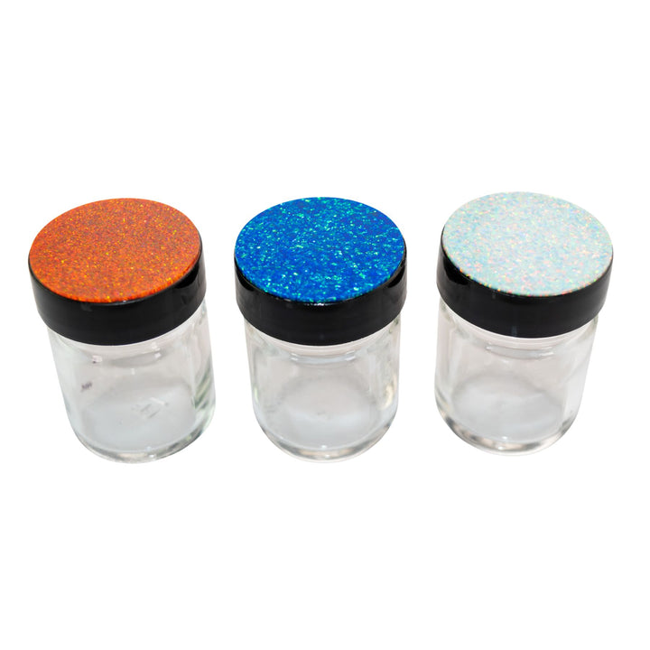 "Three clear jars with colorful glittery lids on a white background," - Up N Smoke.