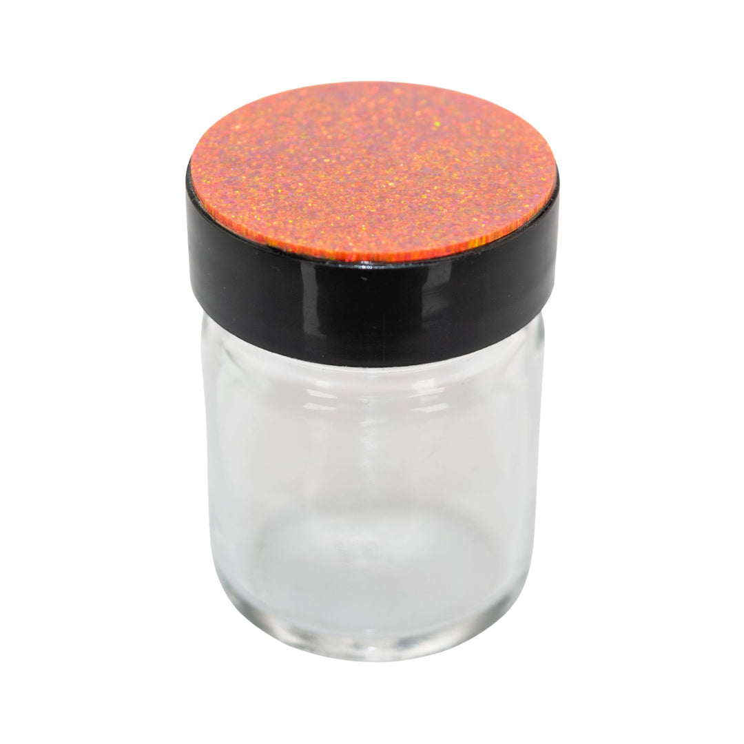 "Clear glass jar with a black lid and orange speckled top on a white background," - Up N Smoke.