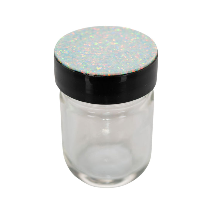"Clear glass jar with a black lid and colorful speckled top on a white background," - Up N Smoke.
