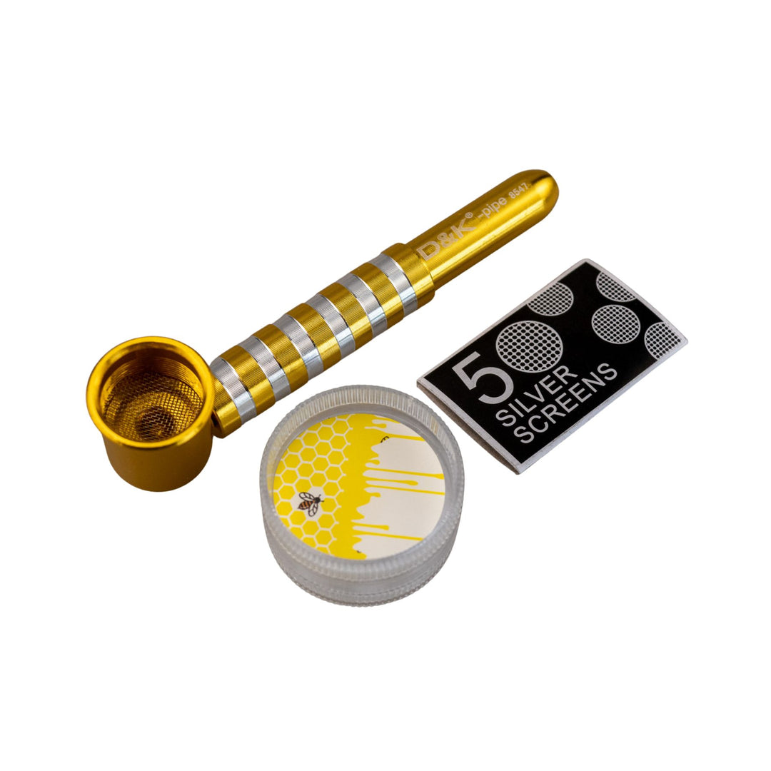 "Gold D&K Metal Stripe Pipe next to the included two-piece grinder and a package of five silver screens," - Up N Smoke.
