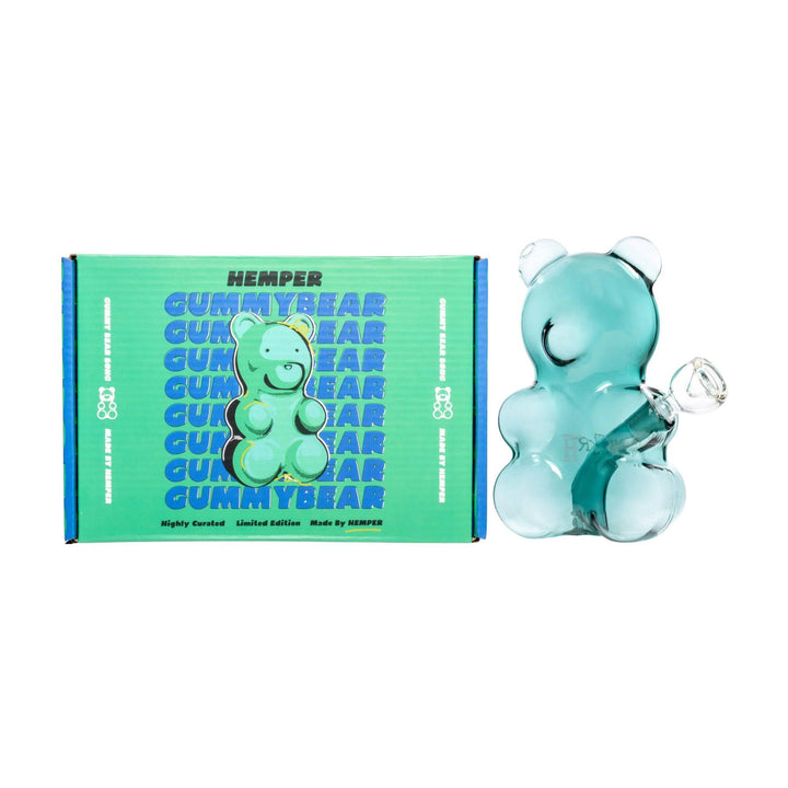"Glass Gummy Bear Water Pipe next to green packaging on a white background," - Up N Smoke.