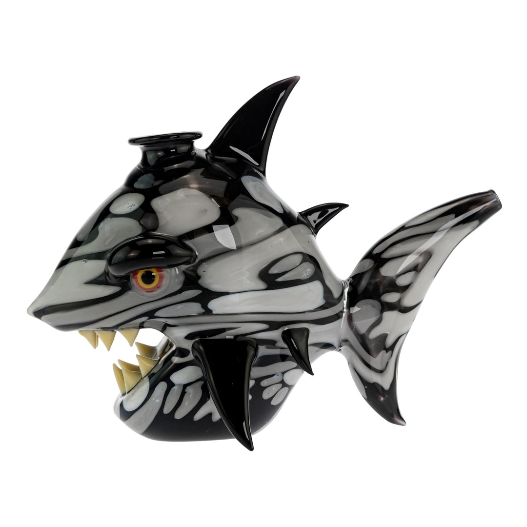 "Left side of a Niko Cray Heady Water Pipe with black and white swirls, black fins, yellow teeth and eyes, on a white background," - Up N Smoke.