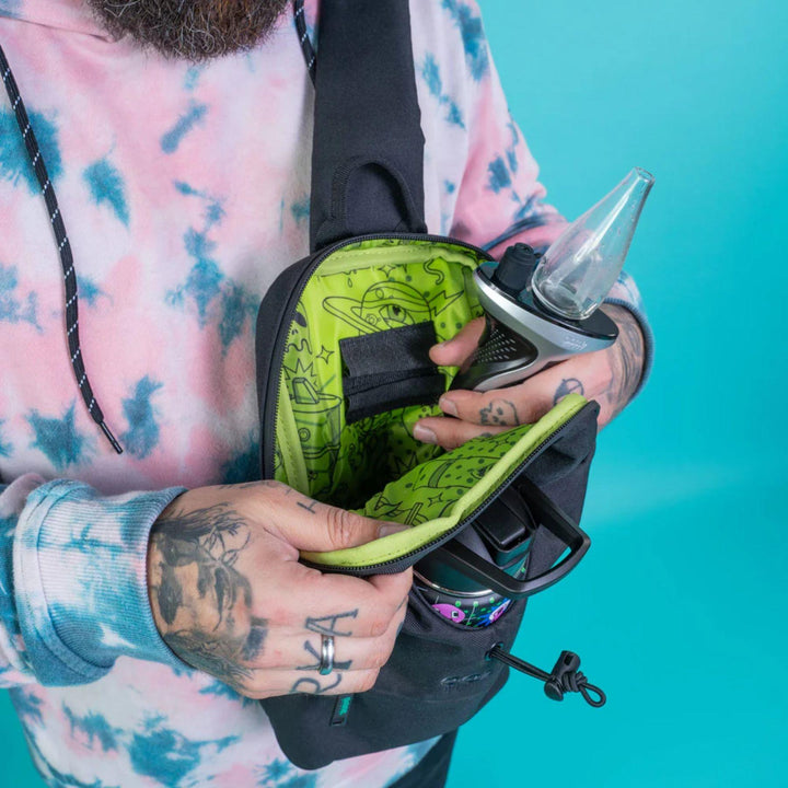 "Person holding a black and green bag with a turquoise background," - Up N Smoke.