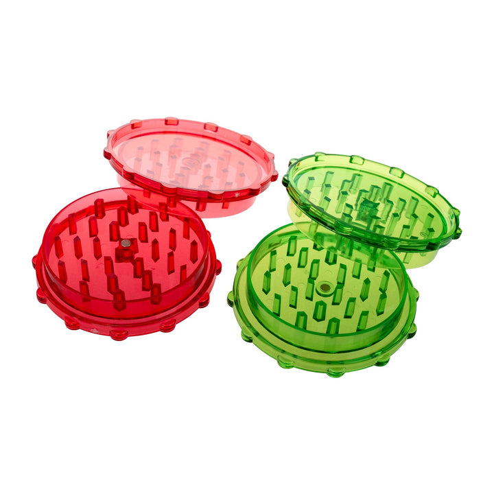 "Two plastic 2-piece grinders in the colors red and green on a white background. These tools are 1'' tall and 3'' wide and feature sharp grinding teeth on both sides," - Up N Smoke.
