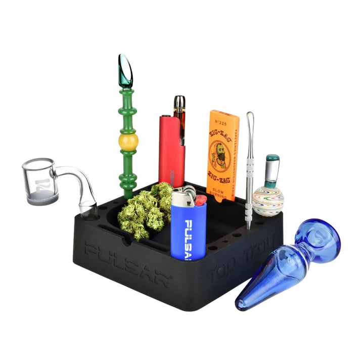 "Black organizer with smoking accessories including a blue herb spoon, glass dab tool, and colorful items on a white background," - Up N Smoke.