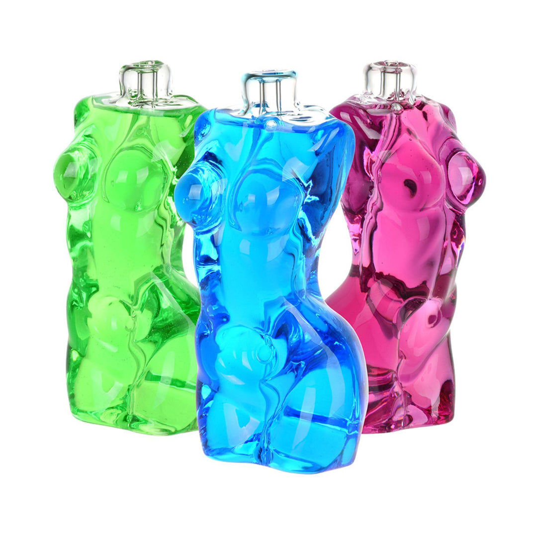 "Three colorful Pulsar Buxom Glycerin Hand Pipes in the shape of a woman's body on a white background," - Up N Smoke.