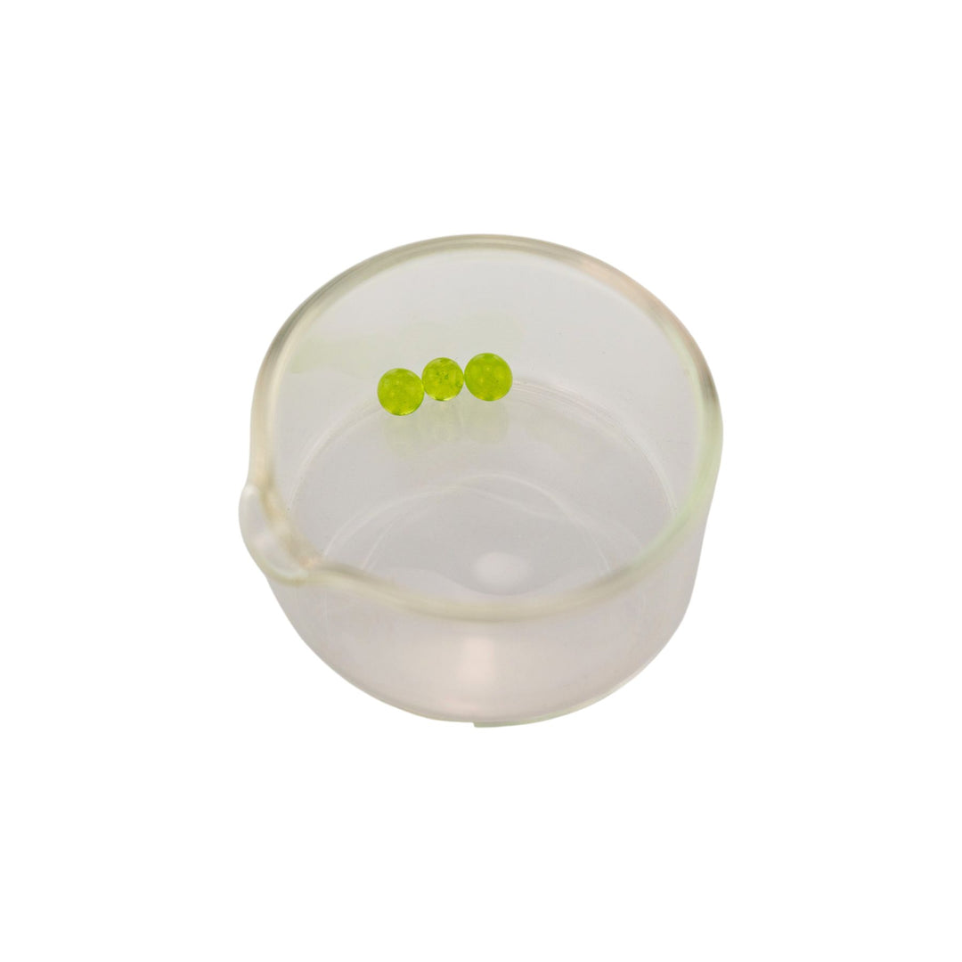 "Clear plastic container with three green carb caps inside that go with a Sol Fire Glass Weed Fairy Recycler on a white background," - Up N Smoke.