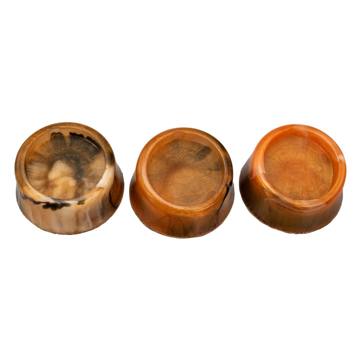 "Three marbled orange resin Puffco Mana Stabilizers on a white background," - Up N Smoke.